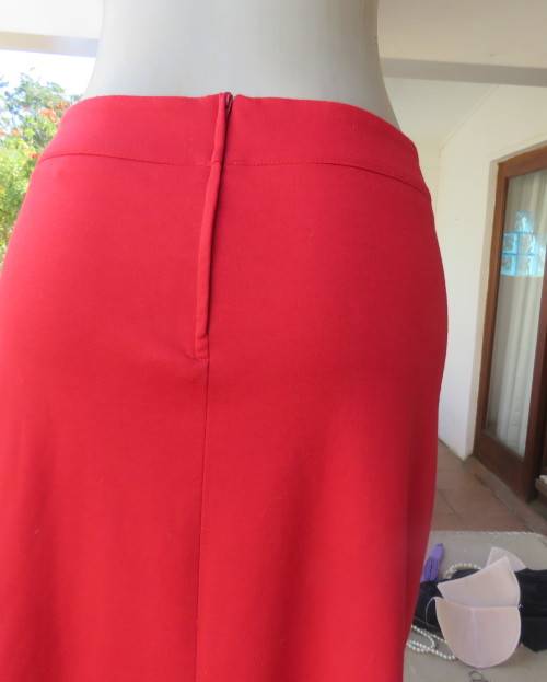 Smart red pencil skirt in red jersey fabric with some stretch.Size 42/18. Pleat at back. As new.