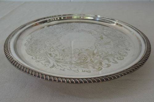AN EXQUISITE VINTAGE SILVER PLATED ROUND FOOTED SERVING TRAY WITH STUNNING ORNATE ENGRAVED DETAILING