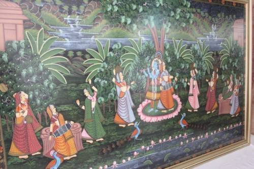 A STUNNING LARGE (1.5m x 1m) PAINTING OF THE HINDU GOD KRISHNA PLAYING THE FLUTE IN A GARDEN