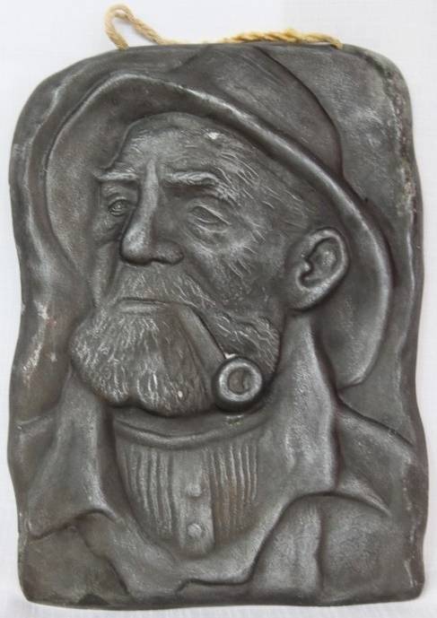 A RARE ANTIQUE HAMMERED WALL HANGING PEWTER TILE OF DORUS RIJKERS THE ''PIPE-SMOKING FISHERMAN''