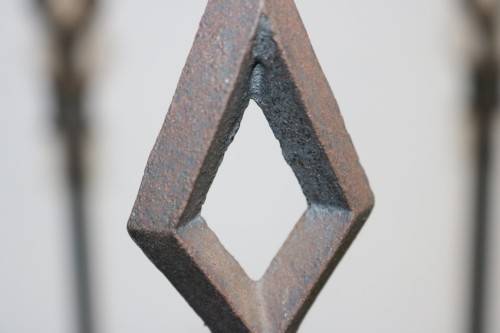An awesome and well made wrought iron fireplace log holder with stunning "arrow" finials