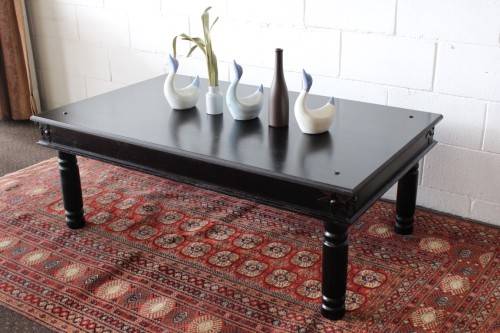 A stunning Indonesian Teak coffee table with clean lines, thick turned legs and carved detailing