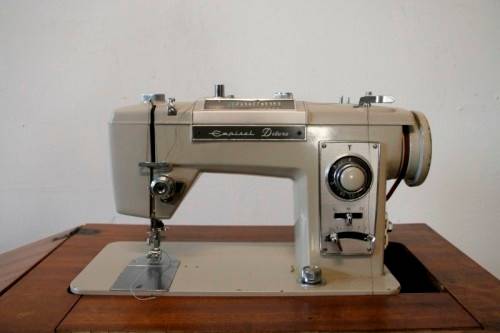 A vintage Empisal deluxe electric sewing machine in its original cabinet w/ accessories, working.