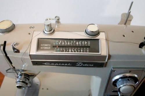 A vintage Empisal deluxe electric sewing machine in its original cabinet w/ accessories, working.