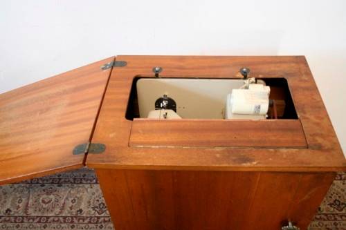 A vintage Empisal deluxe electric sewing machine in its original cabinet w/ accessories, working.