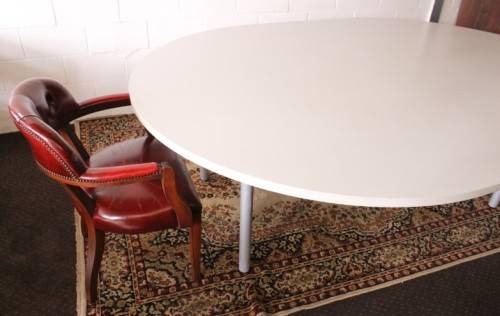 A large oval modern styled, grey painted 8 to 10-seater boardroom table on a sturdy metal frame