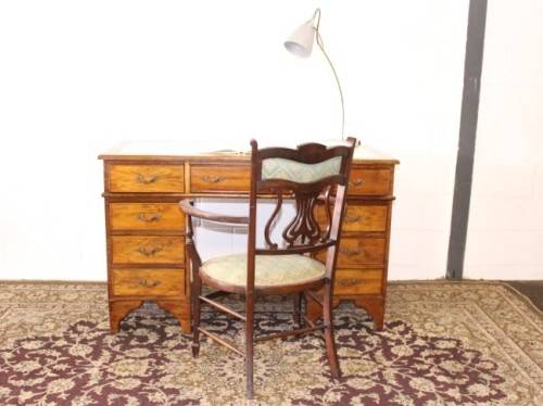 A beautiful vintage knee-hole writing desk w/ an off-white leather top & 9x drawers w/ brass handles