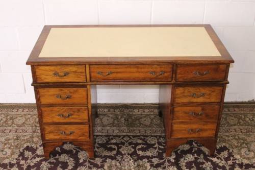 A beautiful vintage knee-hole writing desk w/ an off-white leather top & 9x drawers w/ brass handles