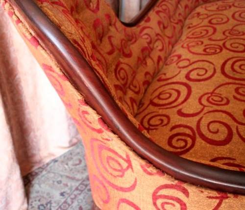 An antique Victorian  "parlour settee" couch w carved detailing and period upholstery on castors.