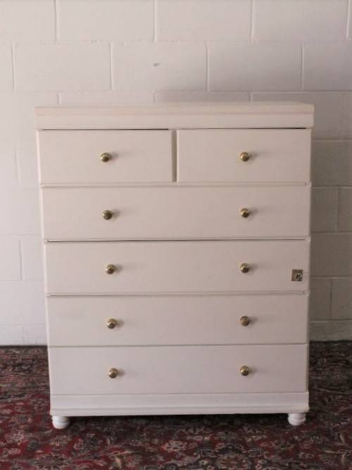 A tall 4-over-2 white painted chest of drawers with brass handles and ample storage space