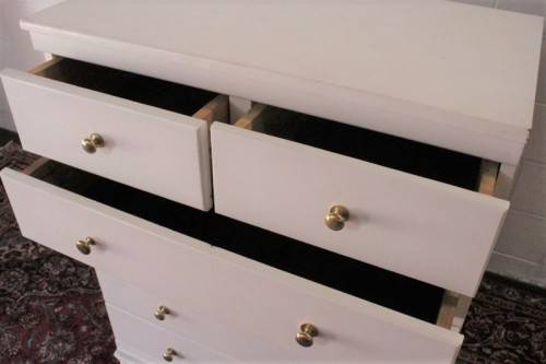 A tall 4-over-2 white painted chest of drawers with brass handles and ample storage space