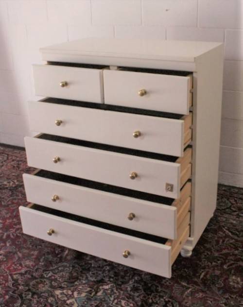 A tall 4-over-2 white painted chest of drawers with brass handles and ample storage space