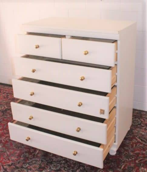A tall 4-over-2 white painted chest of drawers with brass handles and ample storage space