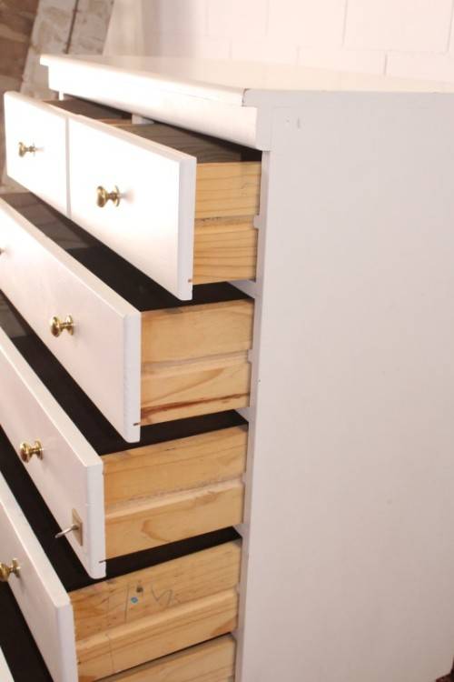 A tall 4-over-2 white painted chest of drawers with brass handles and ample storage space