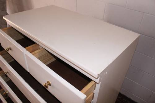 A tall 4-over-2 white painted chest of drawers with brass handles and ample storage space
