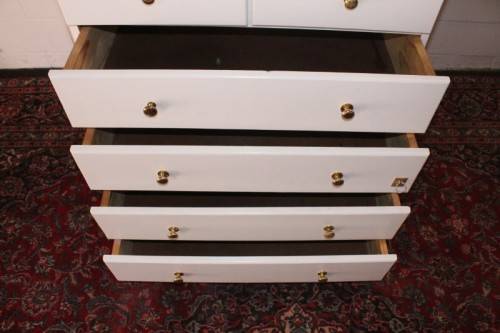 A tall 4-over-2 white painted chest of drawers with brass handles and ample storage space
