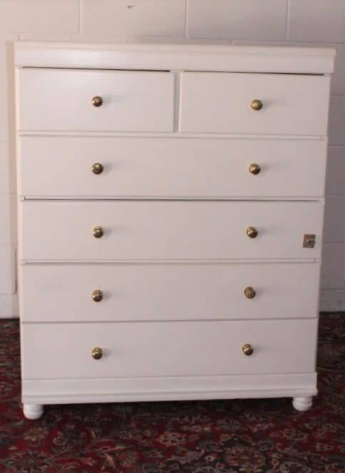 A tall 4-over-2 white painted chest of drawers with brass handles and ample storage space