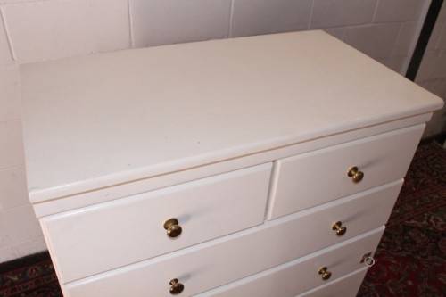 A tall 4-over-2 white painted chest of drawers with brass handles and ample storage space