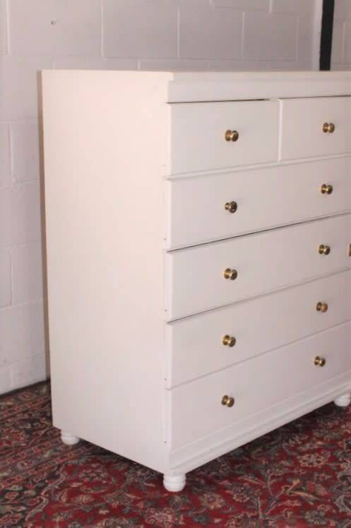 A tall 4-over-2 white painted chest of drawers with brass handles and ample storage space