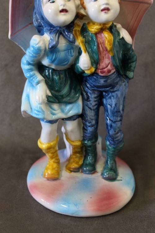 A beautiful porcelain figurine of a young boy and girl under an umbrella, fabulous on display.