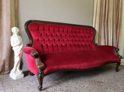A gorgeous antique Victorian 3 seater settee couch w carved detailing and period style upholstery.