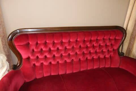 A gorgeous antique Victorian 3 seater settee couch w carved detailing and period style upholstery.