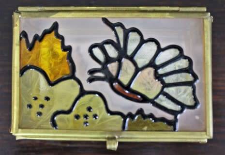A charming coloured glass trinket box with a gold-coloured frame and mirror base. Lifespace Sale