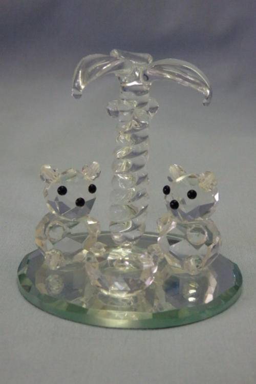 A BEAUTIFUL CRYSTAL ORNAMENT CONSISTING OF TWO HANDMADE CRYSTAL BEARS LOUNGING UNDER A PALMTREE