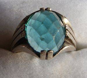 AN OLD STERLING SILVER RING SET WITH AN UNUSUAL STRIKING FACETED BLUE STONE
