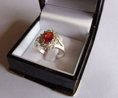 AN EYE CATCHING STERLING SILVER RING WITH A FACETED ORANGE STONE AND FACETED CZ STONES