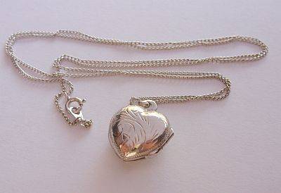 A STERLING SILVER NECKLACE WITH AN ENGRAVED STERLING SILVER HEART LOCKET