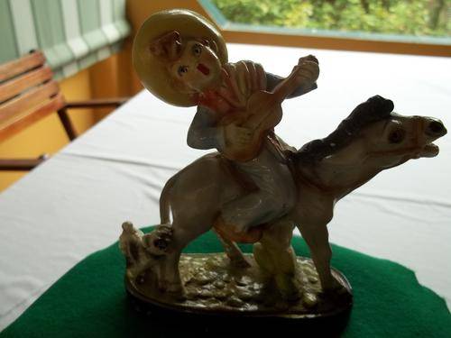Chalkware figurine of little boy playing guitar on donkey's  back with small dog on its side