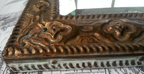 ANTIQUE, RECTANGULAR BEVELED MIRROR SET WITHIN A DECORATIVE PRESSED METAL FRAME