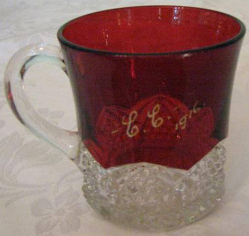 DATED FOR 1916,GLASS CUP WITH HANDLE, RED TOP AND DECORATIVE CLEAR GLASS BOTTOM.