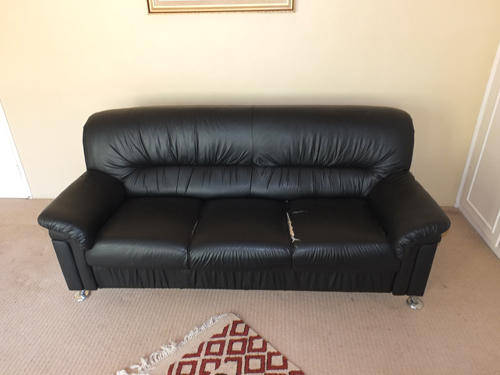 A black faux leather 3 seater sofa and single chair.