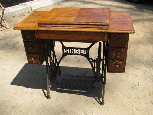 AN ANTIQUE SINGER SEWING MACHINE IN ORNATE CAST IRON AND OAK CABINET
