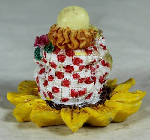 Ceramic clown sitting in a sunflower holding a bunch of roses