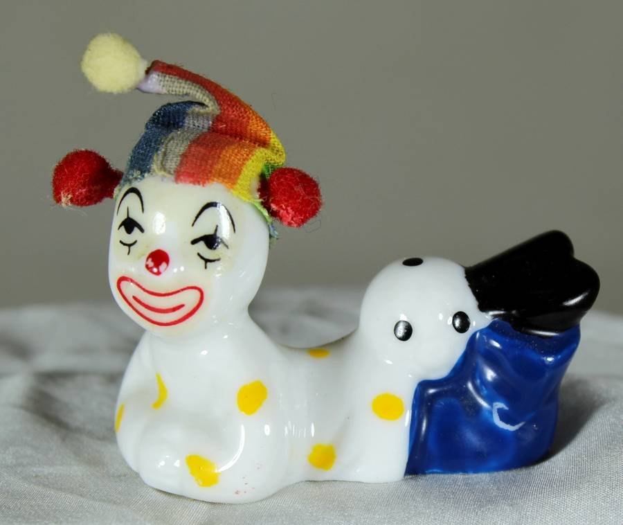 Clown laying on stomach with ball behind legs