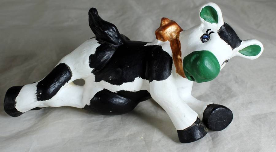 Ceramic cow sitting on a fence