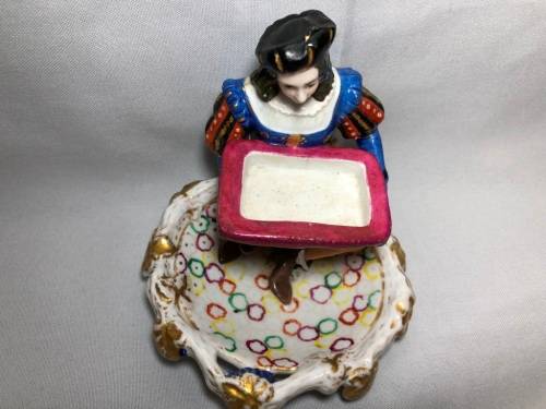 PORCELAIN FIGURINE OF A BOY SITTING HOLDING A SERVING DISH