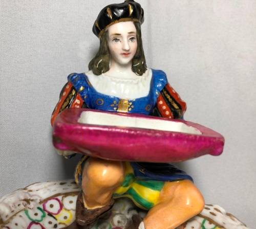 PORCELAIN FIGURINE OF A BOY SITTING HOLDING A SERVING DISH