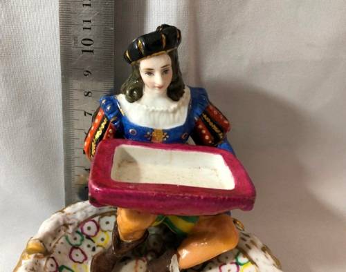 PORCELAIN FIGURINE OF A BOY SITTING HOLDING A SERVING DISH