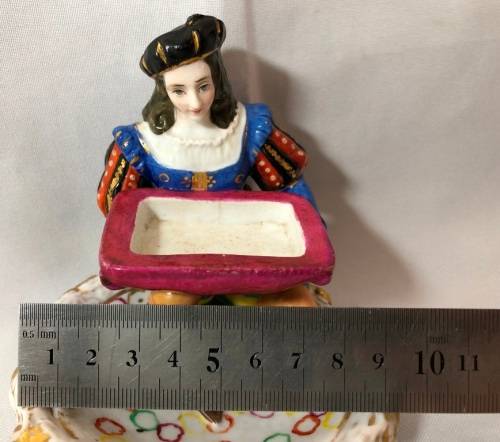 PORCELAIN FIGURINE OF A BOY SITTING HOLDING A SERVING DISH
