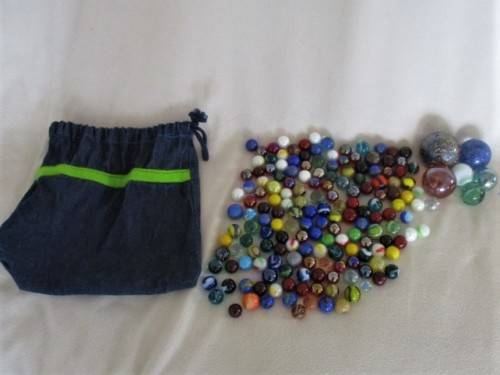 A DENIM DRAWSTRING BAG CONTAINING 160 GOOD QUALITY MARBLES PLUS 6 SHOOTERS IN VARIOUS SIZES