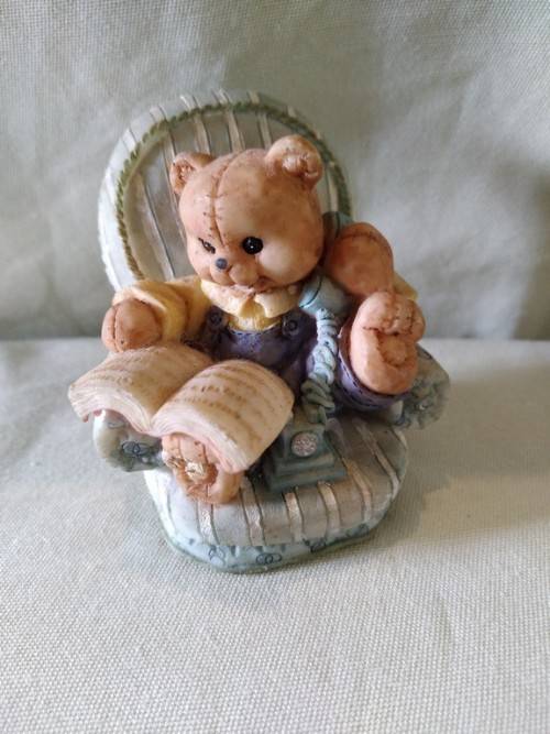 Teddy bear in blue armchair talking on the telephone
