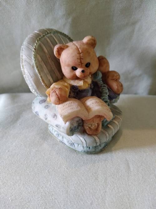 Teddy bear in blue armchair talking on the telephone