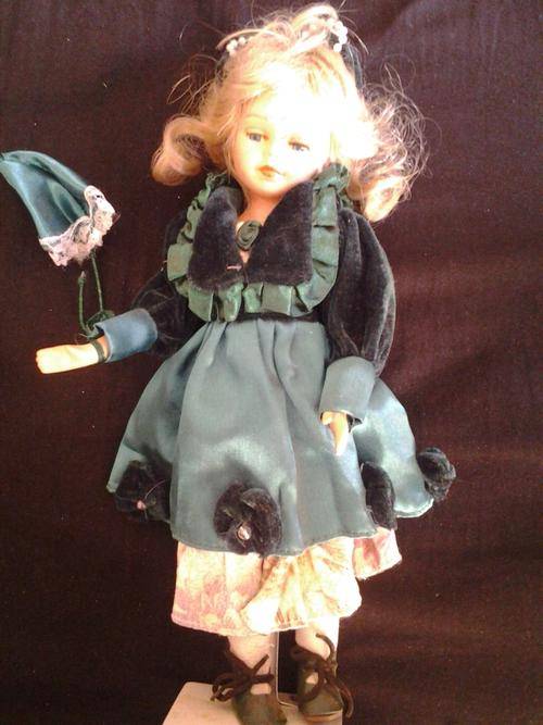 Porcelain doll with green clothes and umbrella
