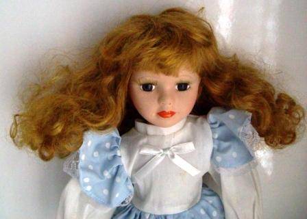 Porcelain doll with gold curly hair and with lovely eyelashes.