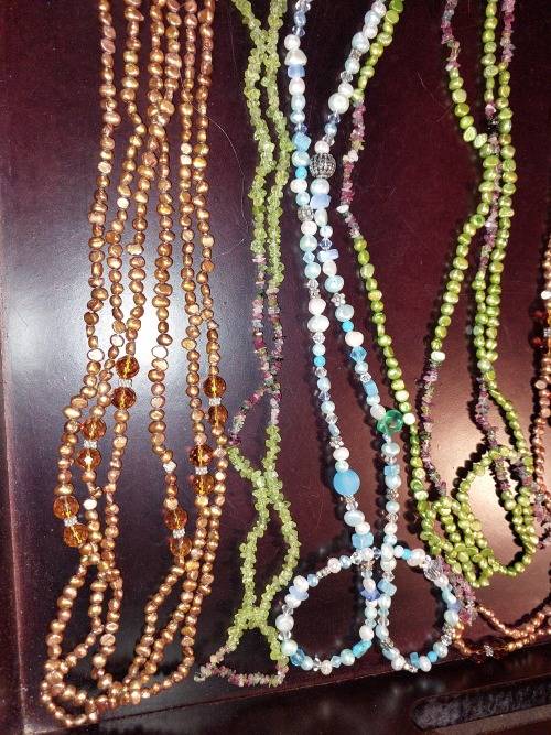 A COLLECTION OF MULTI COLOURED EXTRA LENGTH PEARL NECKLACES SOLD AS IS