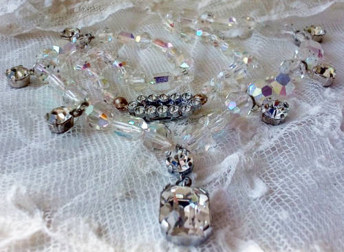 A SPARKLING SINGLE STRAND CRYSTAL NECKLACE WITH 6 SIDE DROP CRYSTALS AND A CENTRAL DROP PENDANT